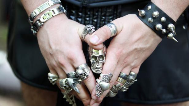 Ein Mann mit zahlreichen Ringen mit Totenkopfmotiven und einem Nietarmband.