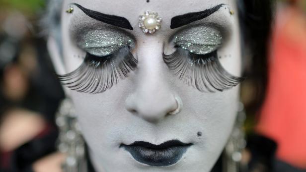 Nahaufnahme eines Gesichts mit weißer Farbe, dramatischem Make-up und langen falschen Wimpern.