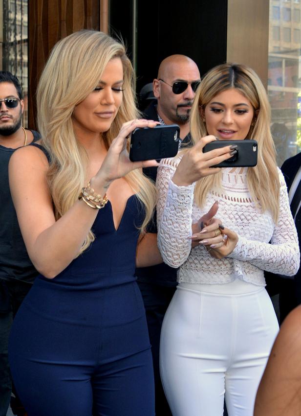 Khloé Kardashian und Kylie Jenner machen Fotos mit ihren Smartphones.
