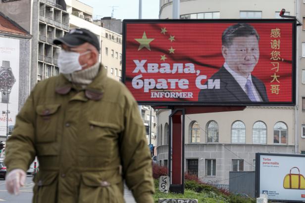 FILE PHOTO: A man wearing a protective mask passes by a billboard depicting Chinese President Xi Jinping in Belgrade, Serbia