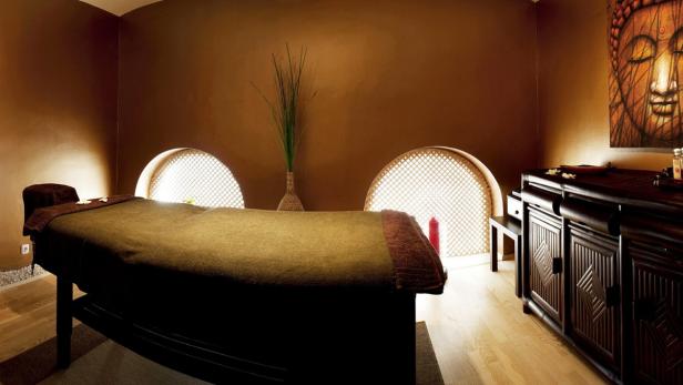 Ein Massagetisch in einem entspannenden Spa-Raum mit Buddha-Dekoration.