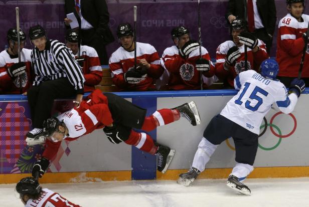 Ein Eishockeyspieler stürzt vor der Bank der österreichischen Mannschaft.