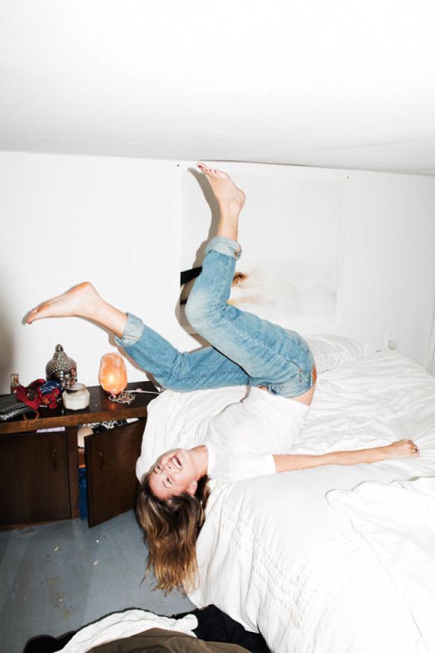 Eine junge Frau liegt auf dem Bett und hält die Beine in die Luft.