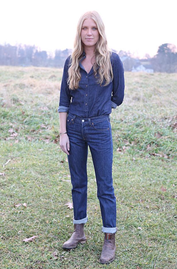 Eine Frau in Jeanshemd und Jeans steht auf einer Wiese.