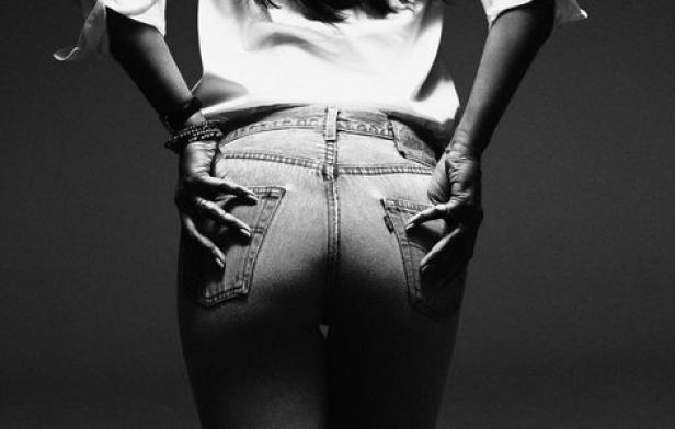 Eine Frau in Jeans posiert mit den Händen in den Gesäßtaschen.