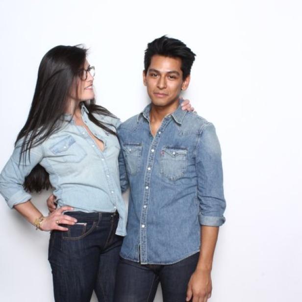 Eine Frau mit Brille und ein Mann posieren in Jeanshemden vor einem weißen Hintergrund.