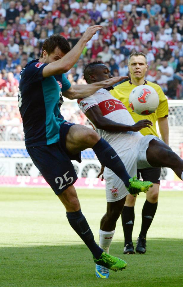 Zwei Fußballspieler kämpfen um den Ball vor den Augen des Schiedsrichters.