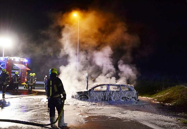 Auf Parkplatz bei der Autobahn abgestellte Unfallautos in Flammen