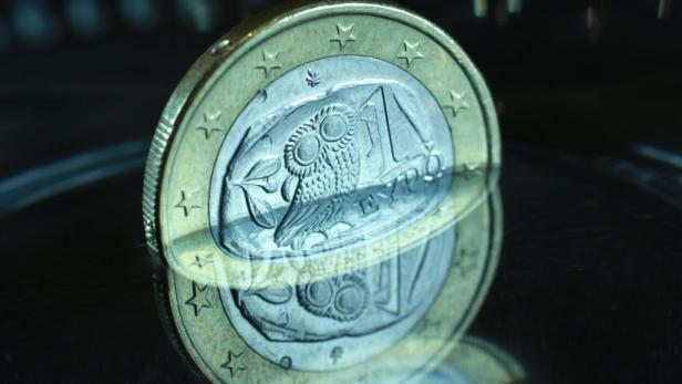 Griechenland, Krise, Euro, Euromünze, Wasser Eine griechische 1-Euro-Münze mit einer Eule darauf liegt auf einer reflektierenden Oberfläche.