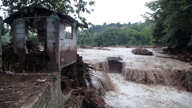 Ein zerstörtes Gebäude steht an einem Fluss nach einer Überschwemmung.