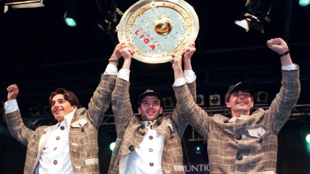 Drei Männer in Trachtenjacken halten die Trophäe der österreichischen Fußball Bundesliga hoch.
