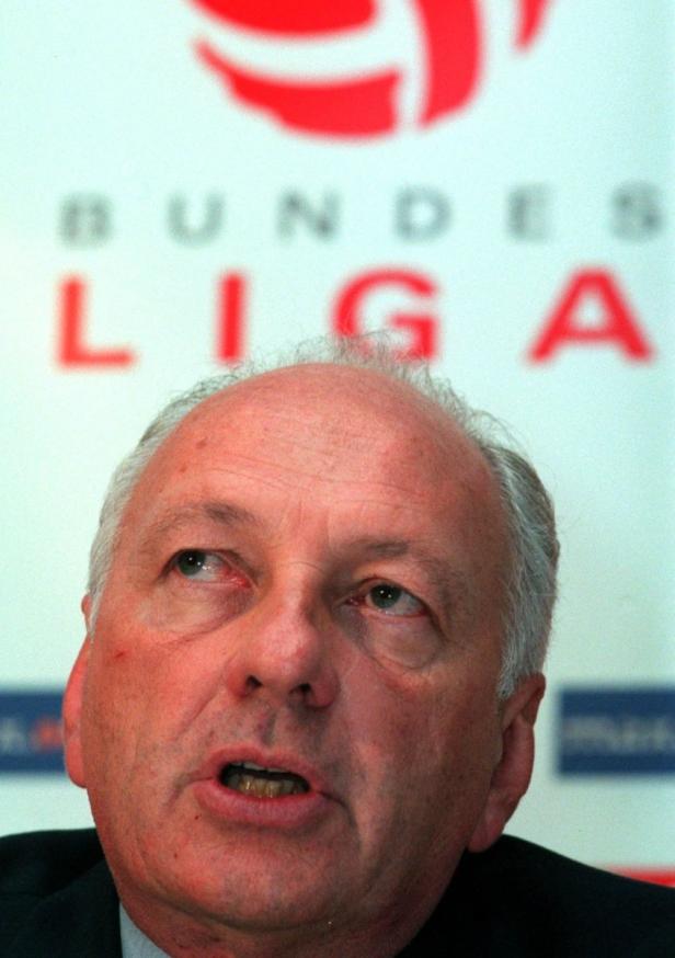 Ein Mann spricht vor einem Bundesliga-Logo.