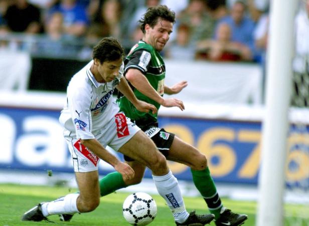 Zwei Fußballspieler kämpfen um den Ball auf dem Spielfeld.