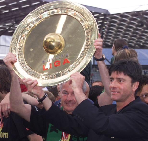 Trainer hält die Meisterschale der Fußball-Bundesliga in die Höhe.