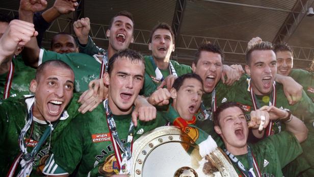Eine Gruppe von Fußballspielern feiert einen Sieg mit der Trophäe.