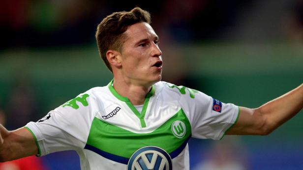 Ein Fußballspieler des VfL Wolfsburg in einem weißen und grünen Trikot jubelt.