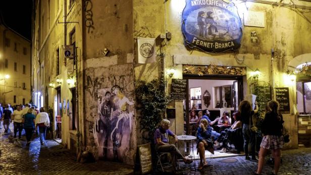 Am Abend sitzen Menschen vor dem „Antico Caffe del Moro“ in Rom.