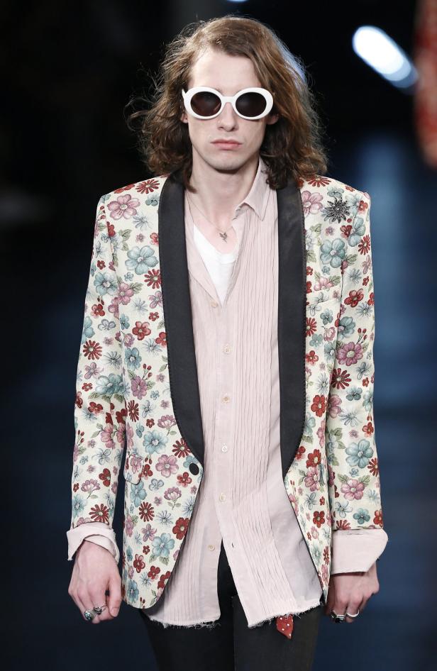 Ein Mann mit langen Haaren und Sonnenbrille trägt ein florales Jackett.