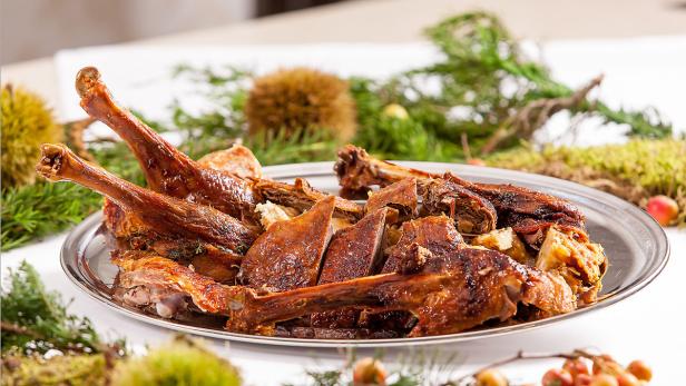 Ein Teller mit gebratener Gans, umgeben von herbstlicher Dekoration.