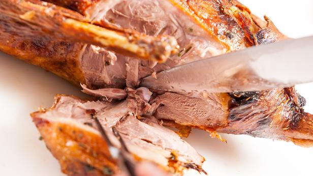 Ein Messer schneidet in eine gebratene Ente.