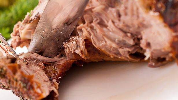 Ein Messer schneidet ein Stück gebratenes Fleisch.