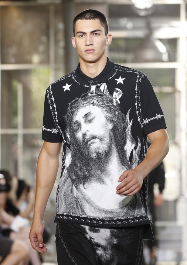 Ein Mann trägt ein schwarzes Poloshirt mit einem Bild von Jesus und Stacheldraht.