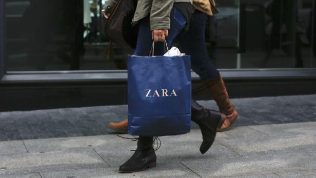 Eine Person trägt eine blaue Einkaufstasche von Zara.
