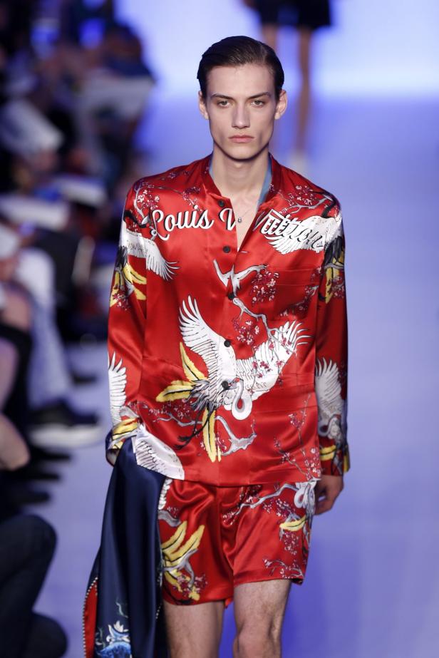 Ein Mann auf dem Laufsteg trägt ein rotes Louis Vuitton Seidenpyjama-Set mit Kranichmotiven.
