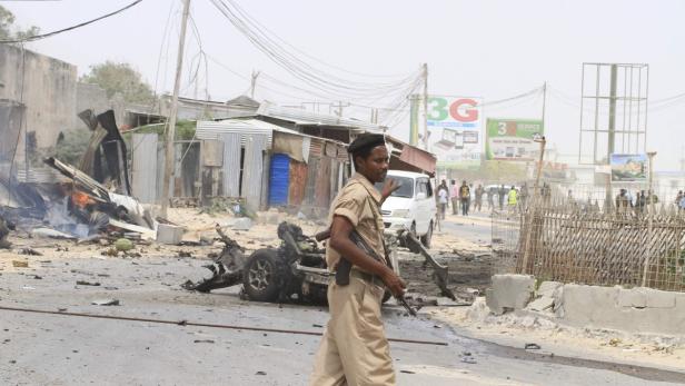 Ein Polizist steht vor einem zerstörten Auto und Trümmern auf einer Straße.
