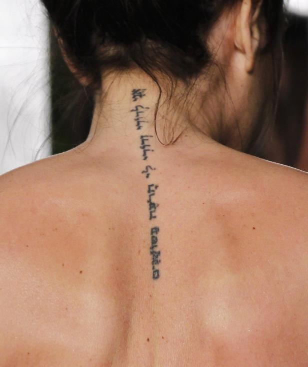 Eine Frau hat ein hebräisches Tattoo auf dem Rücken.