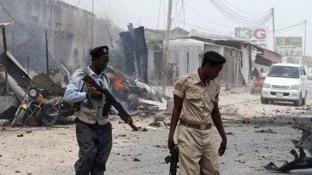 Zwei bewaffnete Männer patrouillieren durch eine zerstörte Stadt.