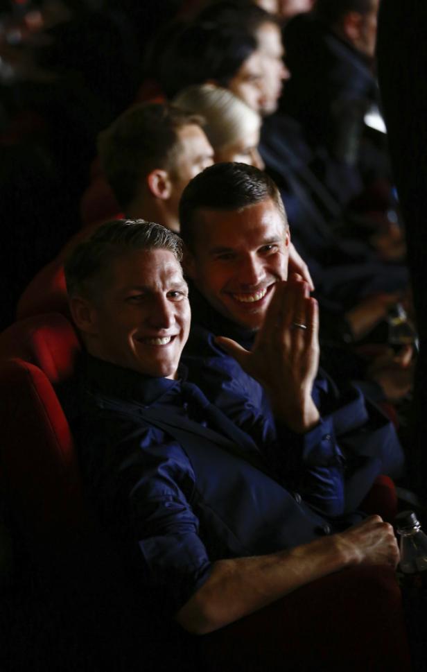 Bastian Schweinsteiger und Lukas Podolski sitzen lächelnd im Publikum.
