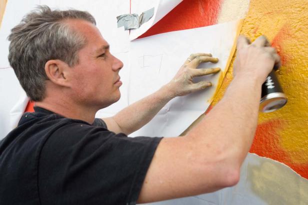 Ein Mann sprüht Farbe auf eine Wand.