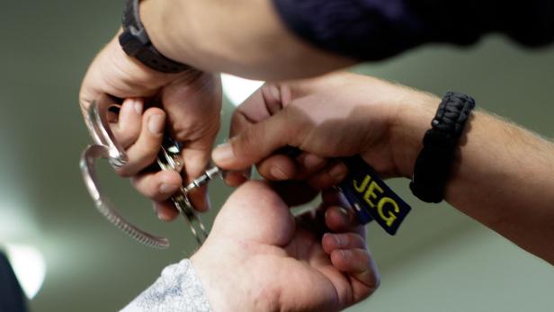 Ein Mann wird mit Handschellen gefesselt.