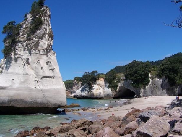 Ein Felsenriff an einem sonnigen Strand mit blauem Himmel.
