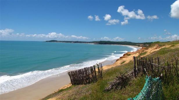 Ein Küstenabschnitt mit türkisfarbenem Wasser und einem Sandstrand unter blauem Himmel.