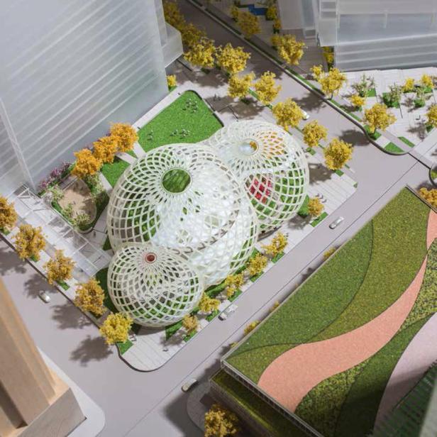 Ein Architekturmodell mit drei kugelförmigen Gewächshäusern in einer städtischen Umgebung.
