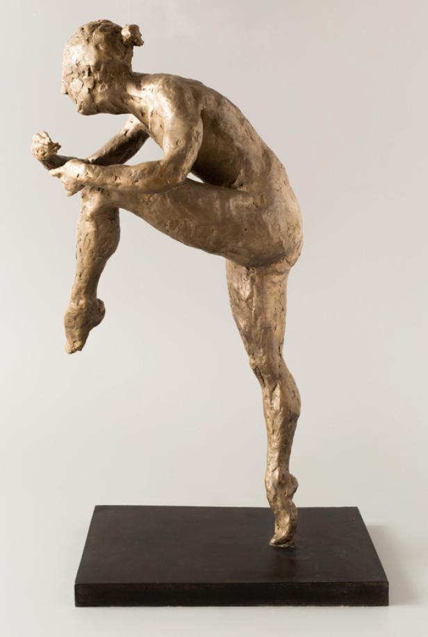 Eine Bronzestatue einer Ballerina, die sich auf ihren Auftritt vorbereitet.