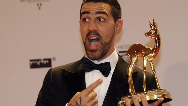 Bushido hält eine goldene Bambi-Statue und zeigt mit dem Finger darauf.
