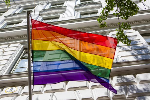 Eine Regenbogenflagge weht vor einem weißen Gebäude.