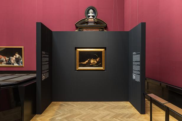 Ein Gemälde eines liegenden Kindes mit Flügeln in einem goldenen Rahmen.