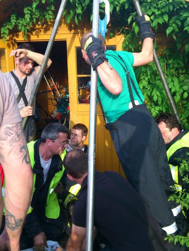 Eine Gruppe von Rettungskräften arbeitet an einer Rettungsaktion vor einem gelben Gebäude.