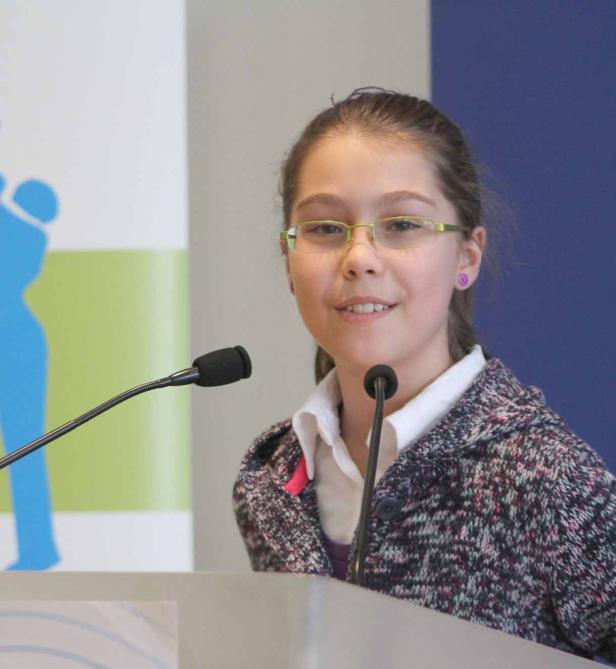 Ein junges Mädchen mit Brille spricht an einem Rednerpult.