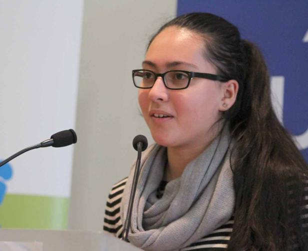 Eine junge Frau mit Brille spricht an einem Rednerpult.