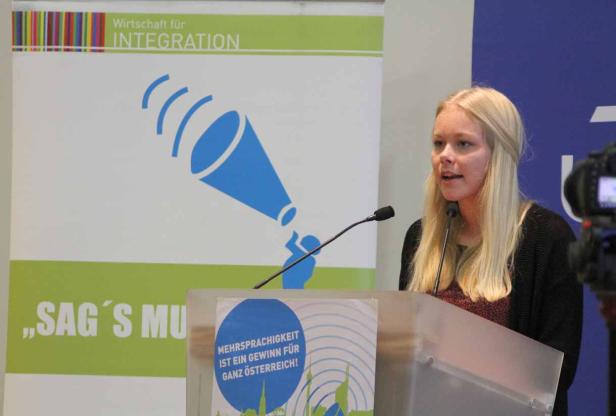 Eine blonde Frau spricht bei einer Veranstaltung zum Thema Integration.