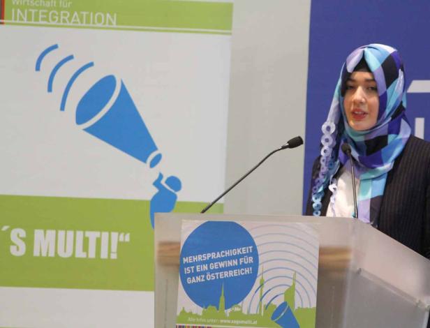 Eine Frau mit Kopftuch spricht bei einer Veranstaltung über Integration und Mehrsprachigkeit.