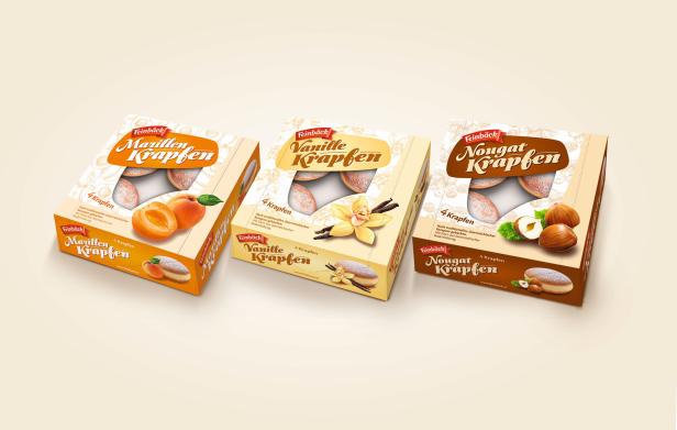 Drei Packungen Feinbäck Krapfen in den Sorten Marille, Vanille und Nougat stehen nebeneinander.
