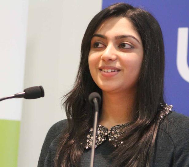 Eine Frau mit dunklen Haaren spricht vor einem Mikrofon.