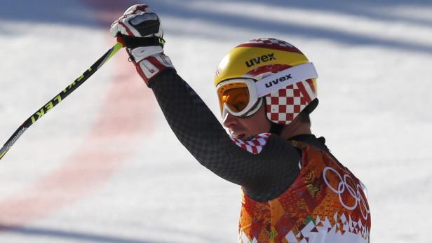 Ein Skirennläufer mit Helm und Skibrille jubelt auf der Piste.