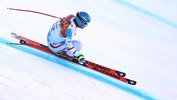 Ein Skirennläufer fährt auf einer schneebedeckten Piste bergab.